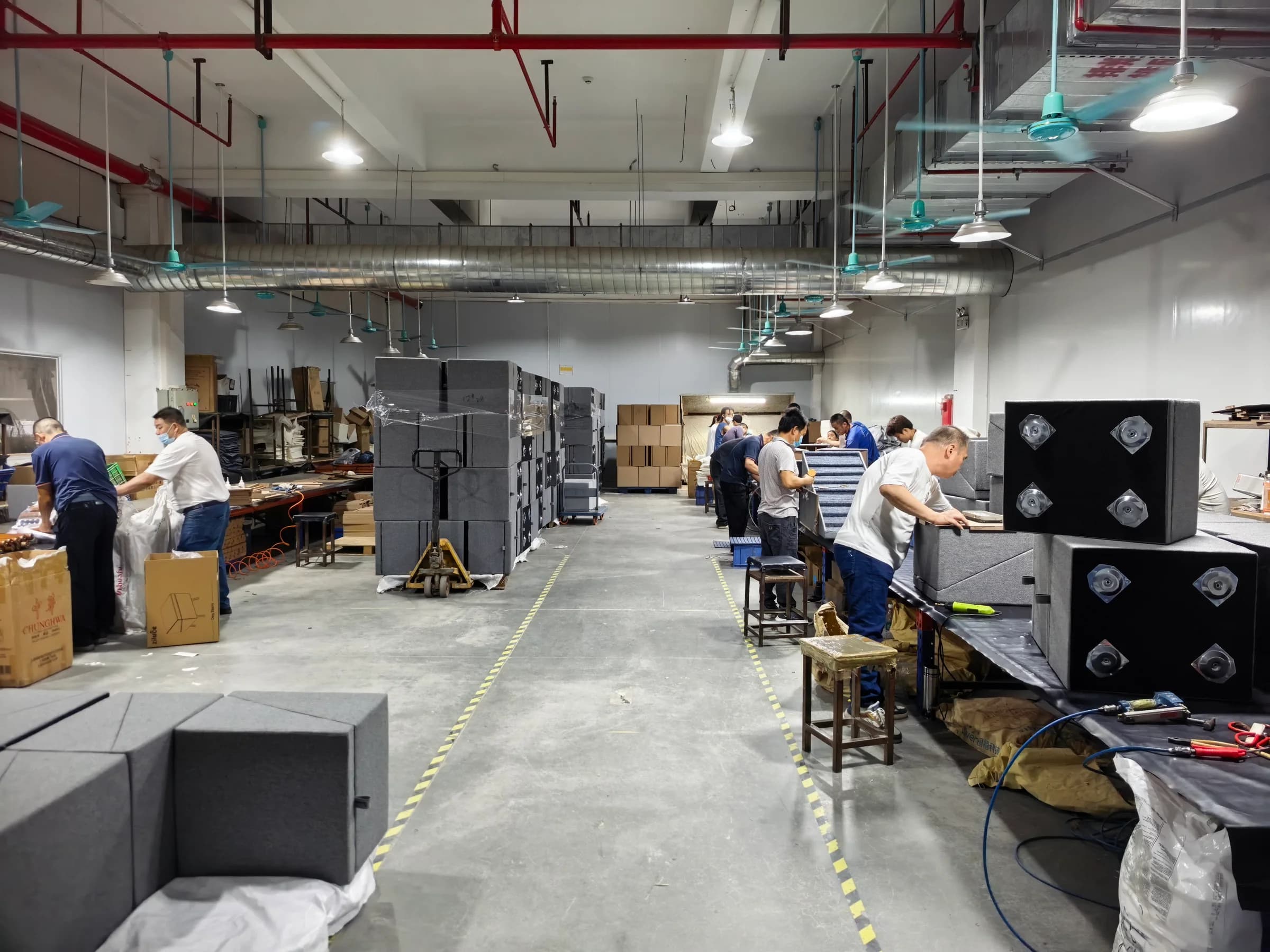 Workshop aisle with employees working at assembly benches and stacked components